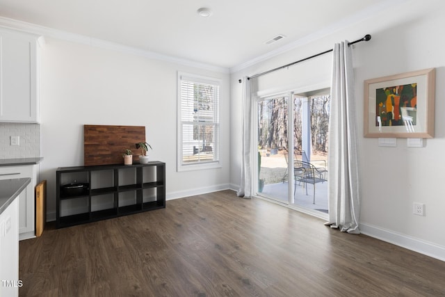 interior space with dark wood-type flooring, crown molding, and baseboards