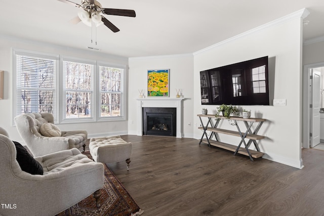 living room featuring a glass covered fireplace, crown molding, baseboards, and wood finished floors