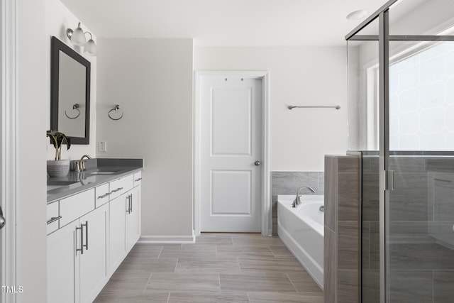 bathroom featuring a garden tub, a stall shower, and vanity