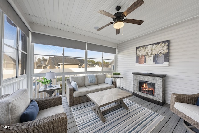 sunroom with a stone fireplace and a ceiling fan