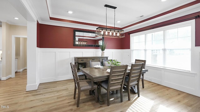 dining room featuring crown molding, light wood-style flooring, visible vents, and a decorative wall