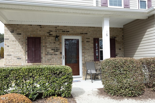 entrance to property featuring brick siding and a porch