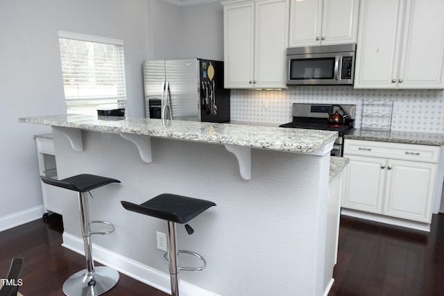 kitchen with light stone counters, decorative backsplash, stainless steel appliances, and dark wood-style flooring