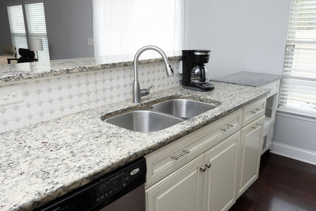 kitchen with a sink, light stone counters, white cabinetry, dishwasher, and dark wood-style flooring