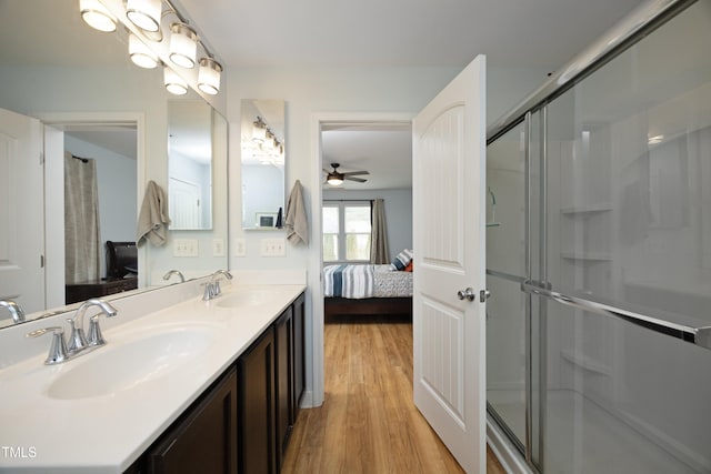 ensuite bathroom with connected bathroom, wood finished floors, a shower stall, and a sink