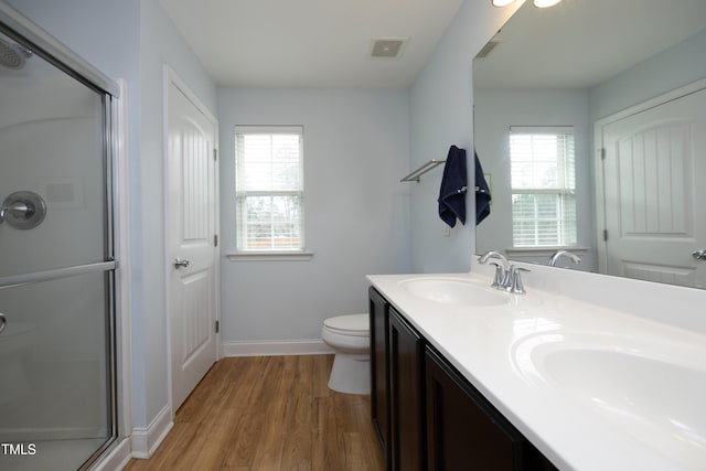 bathroom with wood finished floors, visible vents, double vanity, a sink, and a shower stall