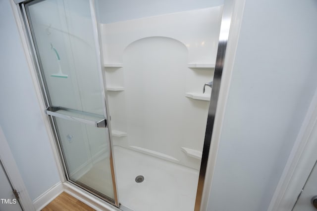 bathroom with wood finished floors and a stall shower