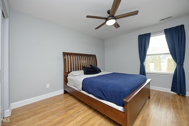 bedroom featuring visible vents, baseboards, ceiling fan, and light wood finished floors