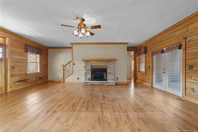 526 Grimble Dr, Linden, NC 28356 - unfurnished living room featuring french doors, a stone fireplace, wooden walls, ceiling fan, and light hardwood / wood-style floors