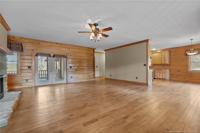 526 Grimble Dr, Linden, NC 28356 - unfurnished living room with light hardwood / wood-style flooring, ceiling fan, wooden walls, ornamental molding, and a stone fireplace