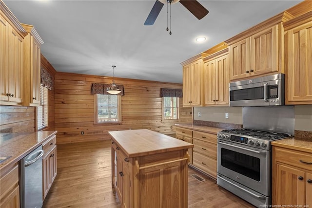 526 Grimble Dr, Linden, NC 28356 - kitchen featuring wood walls, decorative light fixtures, light wood-type flooring, appliances with stainless steel finishes, and a kitchen island