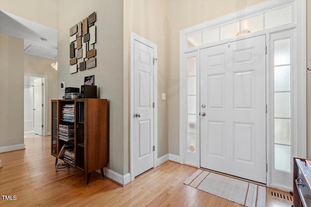 entryway with light wood-type flooring, a healthy amount of sunlight, and baseboards