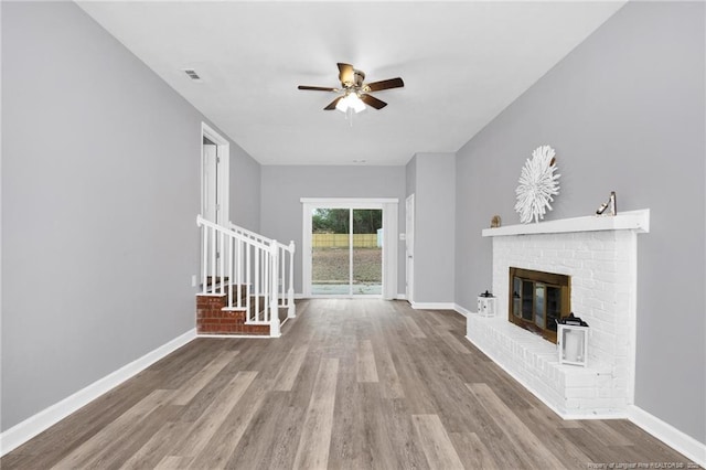 unfurnished living room with ceiling fan, a fireplace, and light wood-type flooring