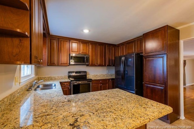 kitchen featuring appliances with stainless steel finishes, sink, light stone counters, and kitchen peninsula