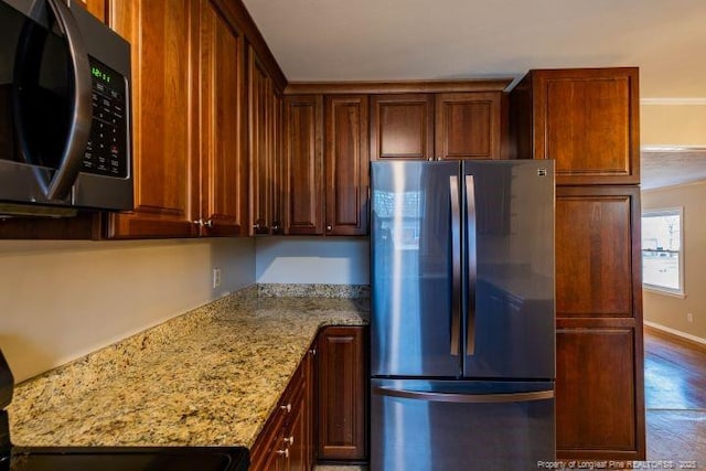 kitchen with stainless steel refrigerator, wood-type flooring, range, and light stone counters