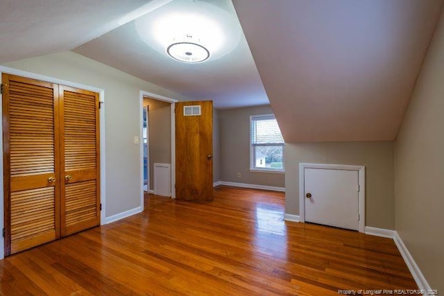 additional living space with wood-type flooring and vaulted ceiling