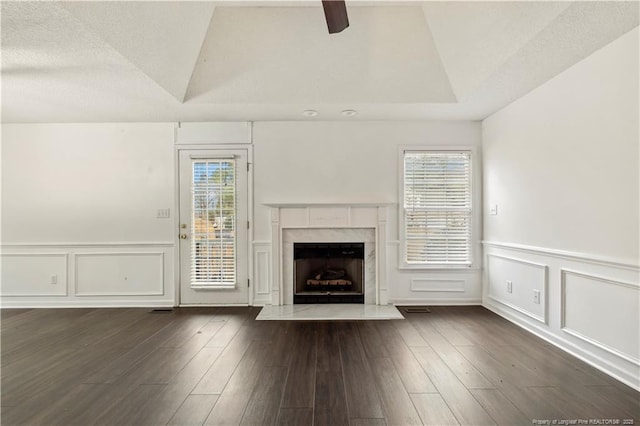 unfurnished living room featuring a raised ceiling, dark wood-type flooring, and a textured ceiling