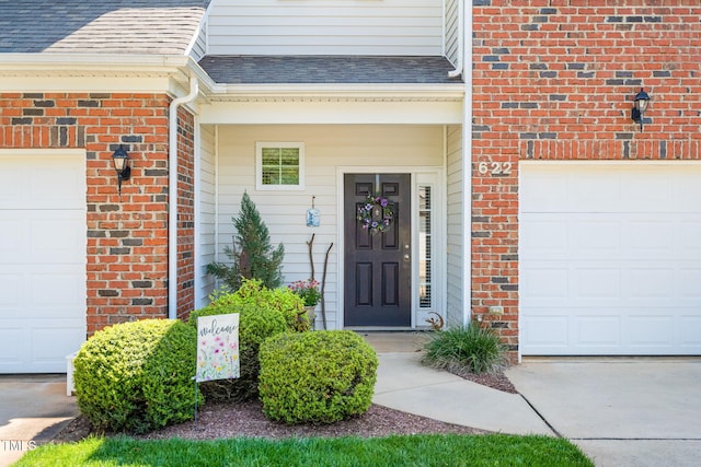 doorway to property with an attached garage, a shingled roof, and brick siding