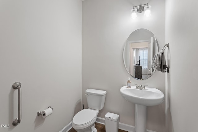 bathroom with wood finished floors, a sink, toilet, and baseboards