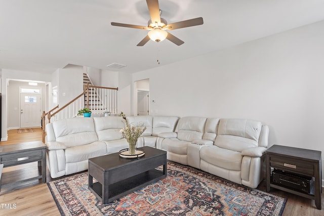 living room with ceiling fan, stairway, wood finished floors, and visible vents