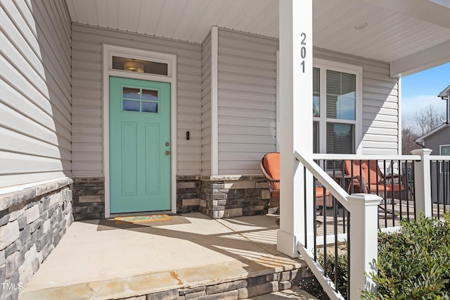 property entrance with stone siding and a porch