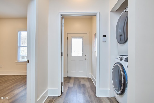 clothes washing area with dark hardwood / wood-style floors and stacked washer / dryer