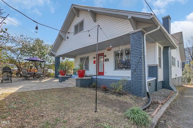 bungalow-style house with covered porch and a chimney