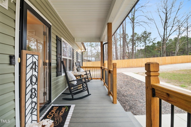 wooden deck featuring covered porch and fence