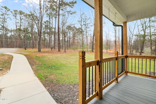 wooden deck featuring covered porch and a yard