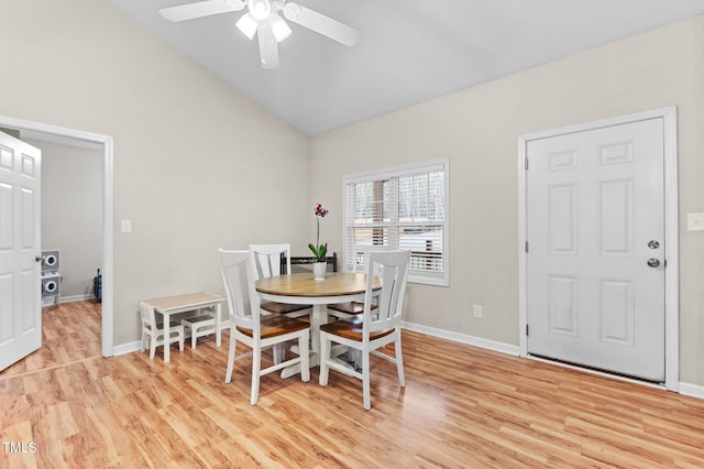 dining room featuring light wood-style floors, lofted ceiling, baseboards, and a ceiling fan