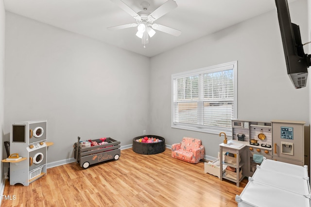 rec room with baseboards, ceiling fan, and light wood finished floors