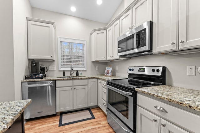 kitchen with stainless steel appliances, light wood-type flooring, white cabinetry, and a sink