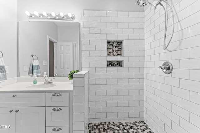 bathroom with tiled shower and vanity