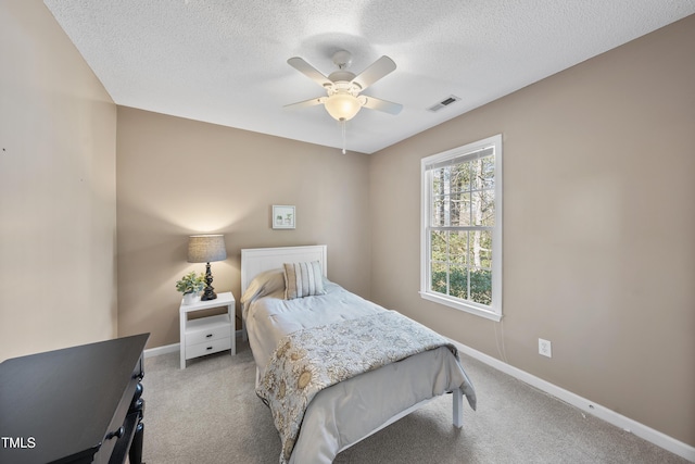 carpeted bedroom with visible vents, a textured ceiling, and baseboards