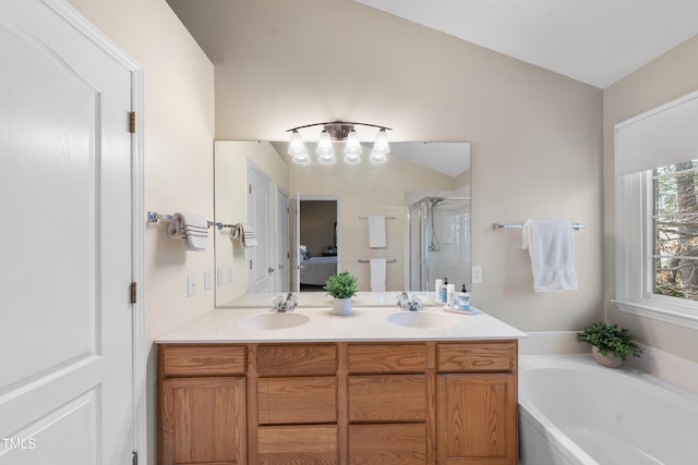 ensuite bathroom featuring double vanity, a stall shower, a garden tub, and a sink