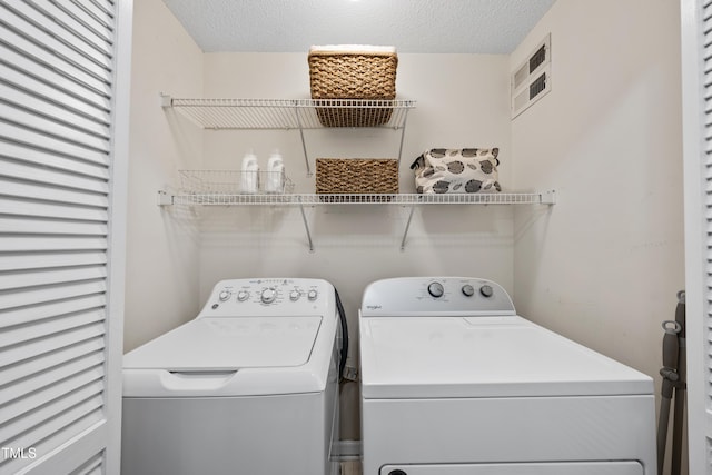 washroom with a textured ceiling and washing machine and clothes dryer