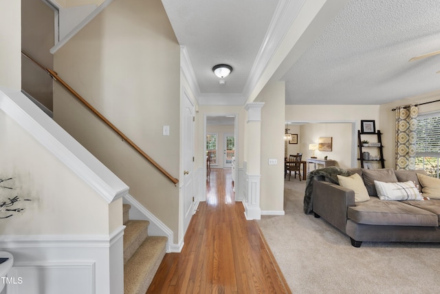 foyer entrance with a textured ceiling, a wealth of natural light, stairs, and decorative columns