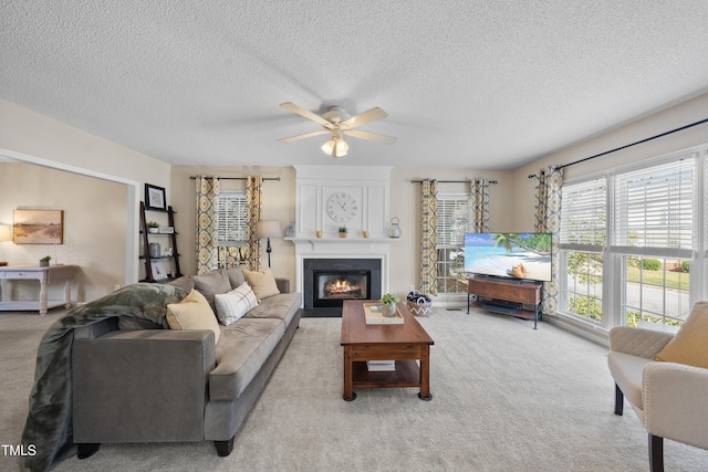 living area with light carpet, a textured ceiling, a fireplace, and a ceiling fan