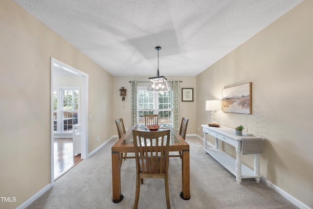 carpeted dining space featuring a textured ceiling and baseboards