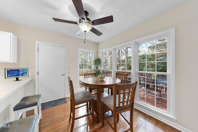 dining room featuring light wood-type flooring, ceiling fan, baseboards, and a textured ceiling