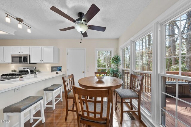 dining area with a textured ceiling, ceiling fan, and wood finished floors