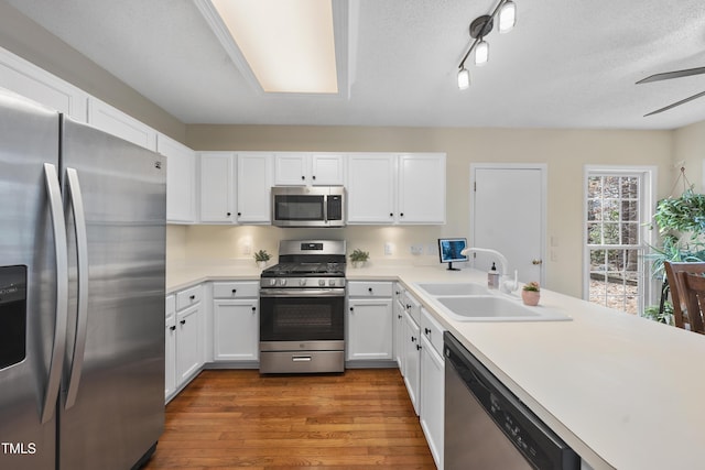 kitchen featuring appliances with stainless steel finishes, light countertops, a sink, and wood finished floors