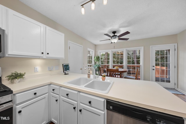 kitchen with a peninsula, appliances with stainless steel finishes, light countertops, and a sink