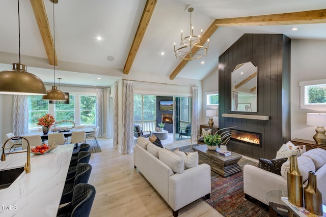 living room featuring an inviting chandelier, a large fireplace, beamed ceiling, and light wood-type flooring