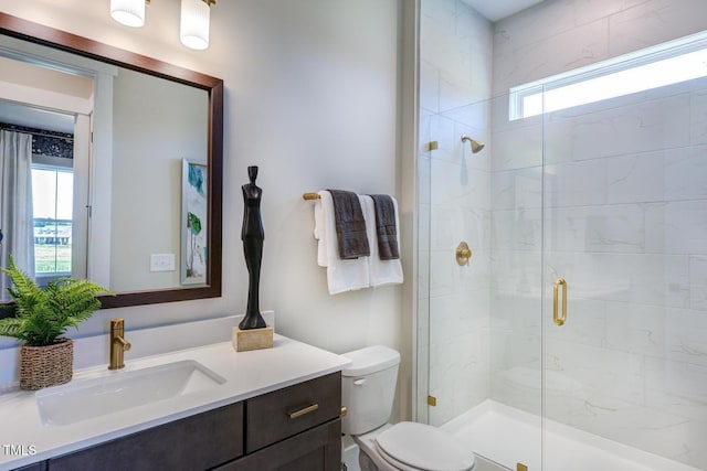 bathroom with vanity, toilet, and a shower with door