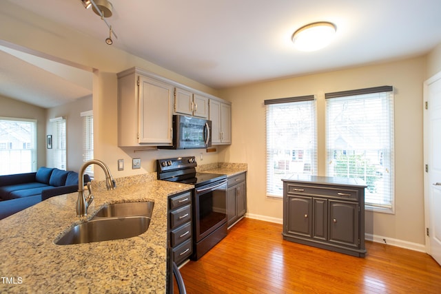 kitchen featuring a sink, baseboards, electric stove, light wood-type flooring, and stainless steel microwave