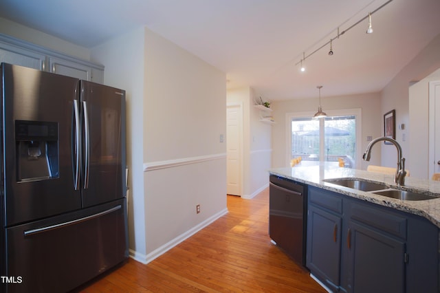 kitchen featuring dishwashing machine, blue cabinets, light stone countertops, stainless steel refrigerator with ice dispenser, and a sink