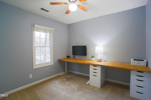 unfurnished office with light carpet, a ceiling fan, visible vents, and baseboards