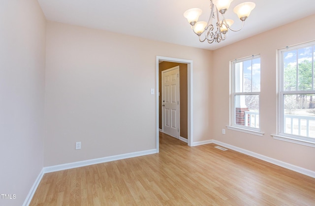 spare room featuring light wood-type flooring, a wealth of natural light, visible vents, and baseboards