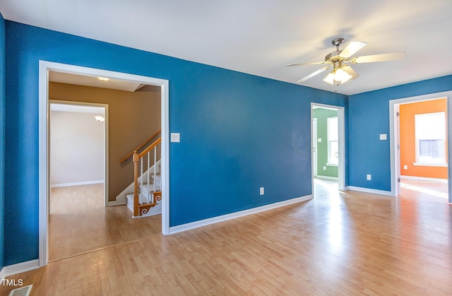 spare room with visible vents, light wood-style floors, ceiling fan, baseboards, and stairs